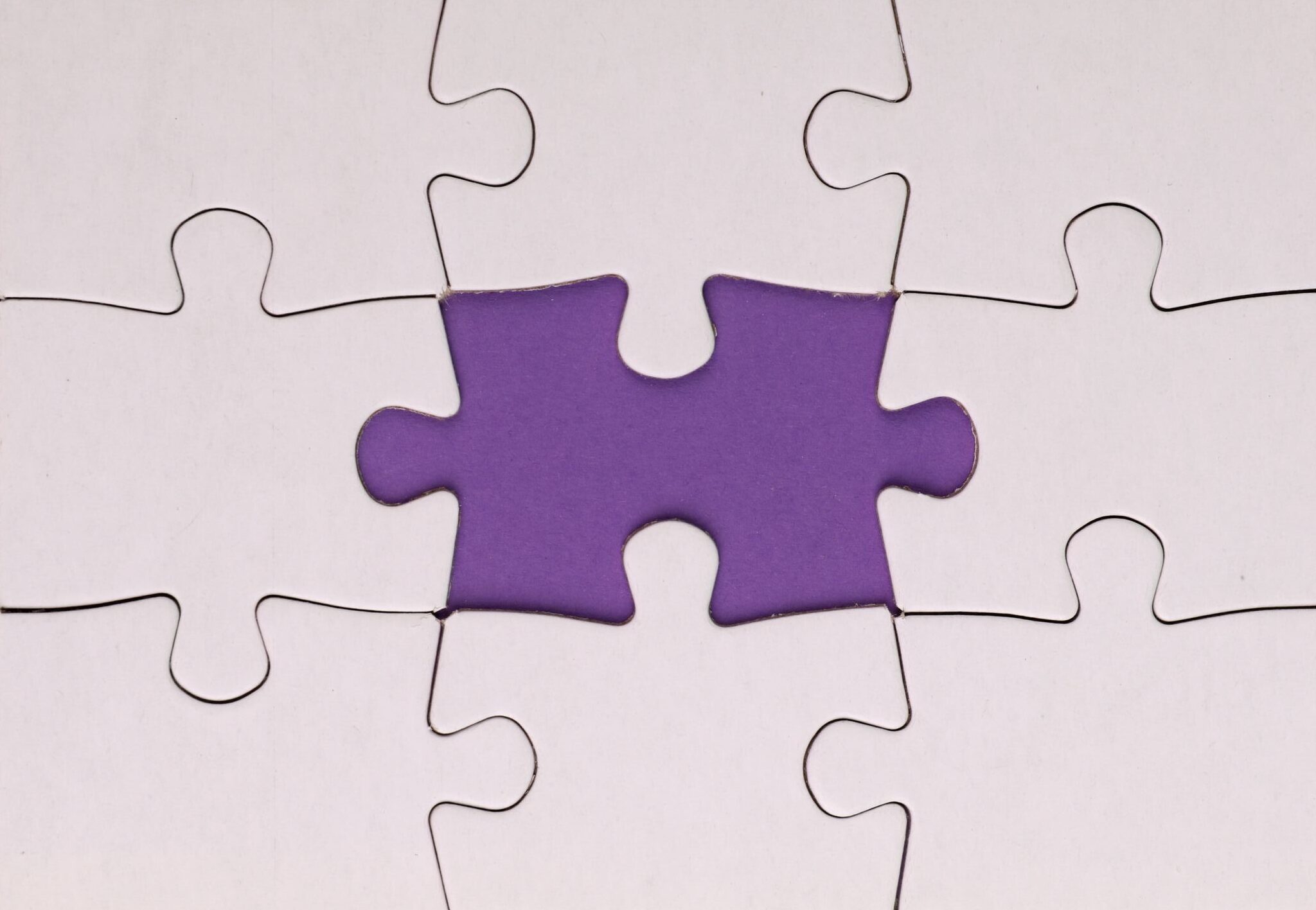 Vertical close-up of a white puzzle with a missing piece, showing a purple background.